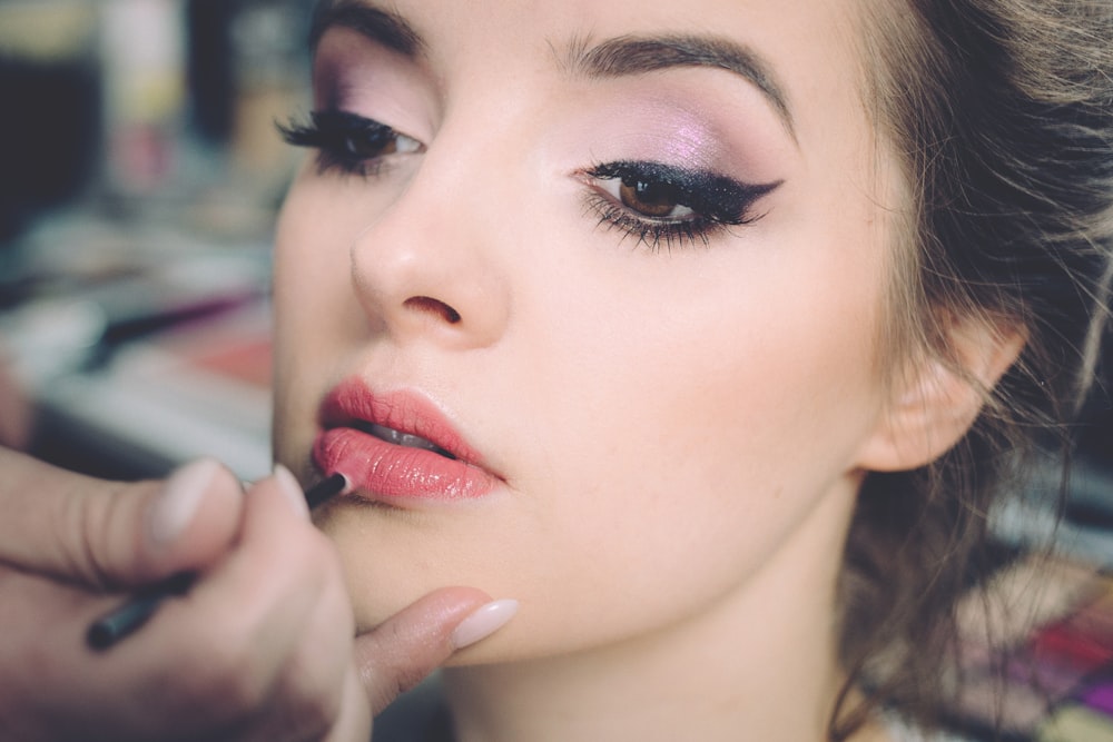 Makeup artist applying lip color to a model in close-up